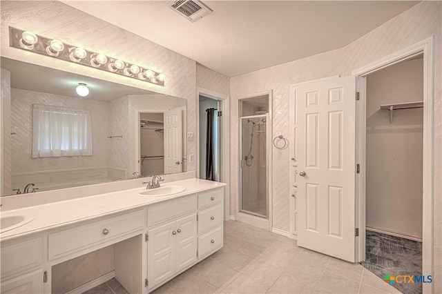 bathroom featuring tile patterned floors, vanity, walk in shower, and a textured ceiling