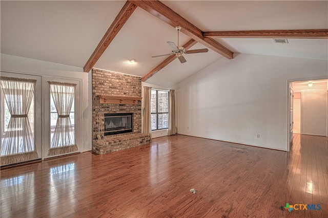 unfurnished living room with lofted ceiling with beams, ceiling fan, wood-type flooring, and a brick fireplace