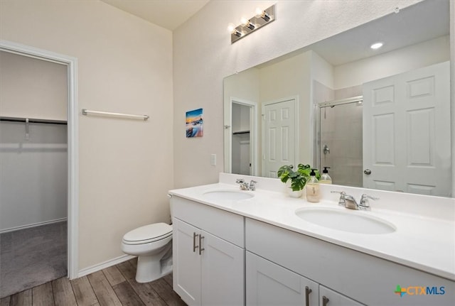 212 Gunther Way, Taylor, TX 76574 - full bathroom with a stall shower, double vanity, a spacious closet, wood finished floors, and toilet
