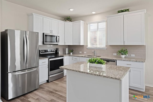 212 Gunther Way, Taylor, TX 76574 - kitchen with stainless steel appliances, a sink, white cabinetry, light wood-style floors, and recessed lighting