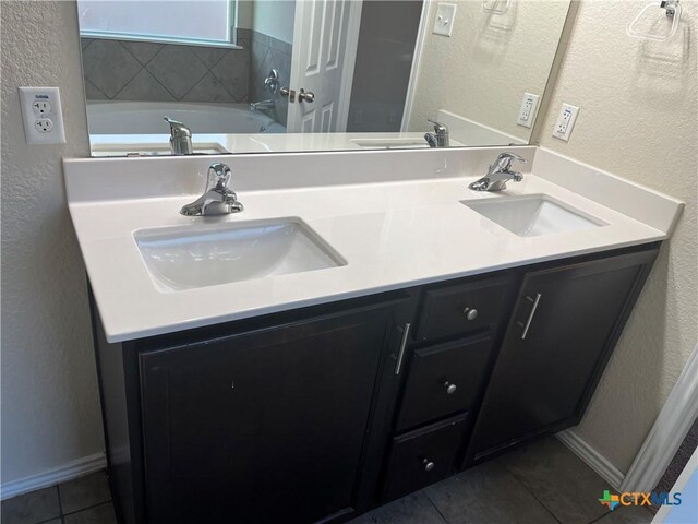 bathroom with a tub to relax in, tile patterned floors, and vanity