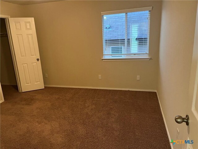 spare room featuring dark colored carpet