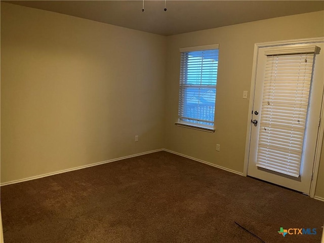 spare room with dark carpet