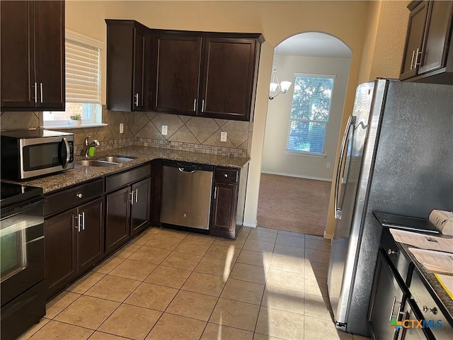 kitchen with light tile patterned flooring, sink, decorative backsplash, dark brown cabinetry, and stainless steel appliances