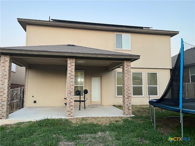 back of house featuring a yard, a trampoline, and a patio area