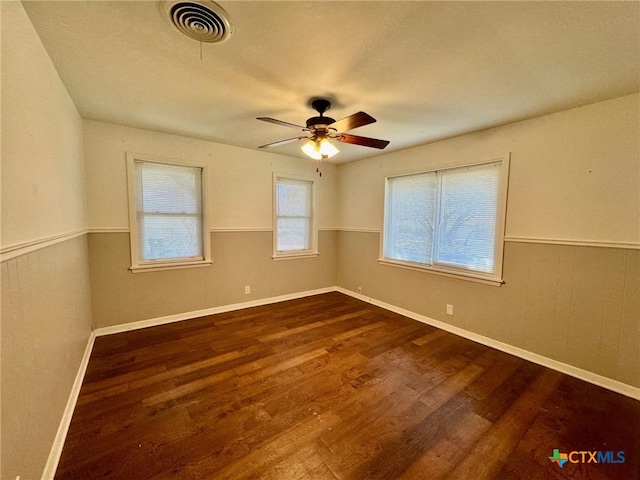 unfurnished room featuring dark wood-type flooring, ceiling fan, and wooden walls