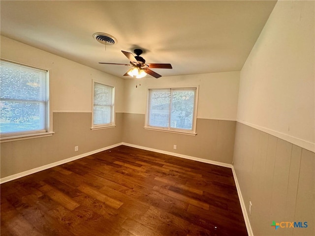 spare room featuring dark wood-type flooring, wood walls, and ceiling fan