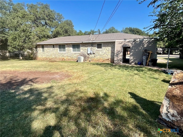 back of property featuring central AC unit and a lawn