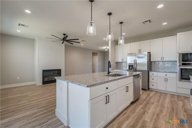 kitchen featuring white cabinetry, sink, and a center island with sink