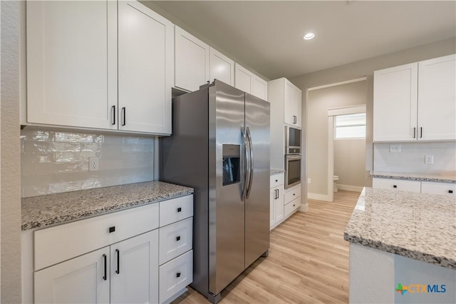 kitchen with stainless steel refrigerator with ice dispenser, white cabinetry, light stone counters, and backsplash