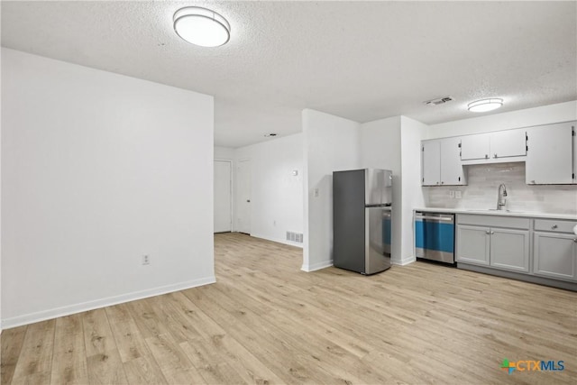 712 N 19th St, Copperas Cove, TX 76522 - kitchen with stainless steel appliances, a sink, a textured ceiling, light wood-style floors, and tasteful backsplash
