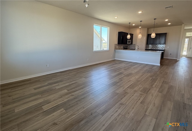 unfurnished living room with a healthy amount of sunlight, dark wood-type flooring, and sink