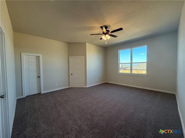 spare room featuring dark colored carpet, ceiling fan, and a textured ceiling