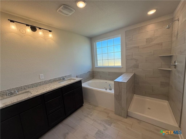 bathroom featuring vanity, shower with separate bathtub, and a textured ceiling