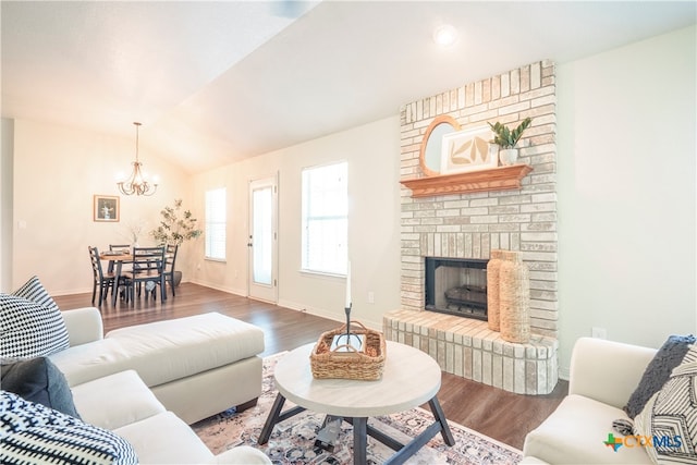 living room featuring hardwood / wood-style floors, a chandelier, vaulted ceiling, and a brick fireplace