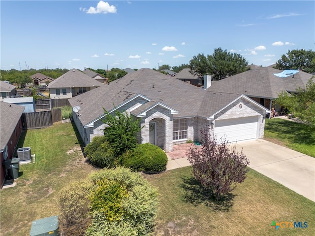 view of front of house with a front lawn, a garage, and central AC