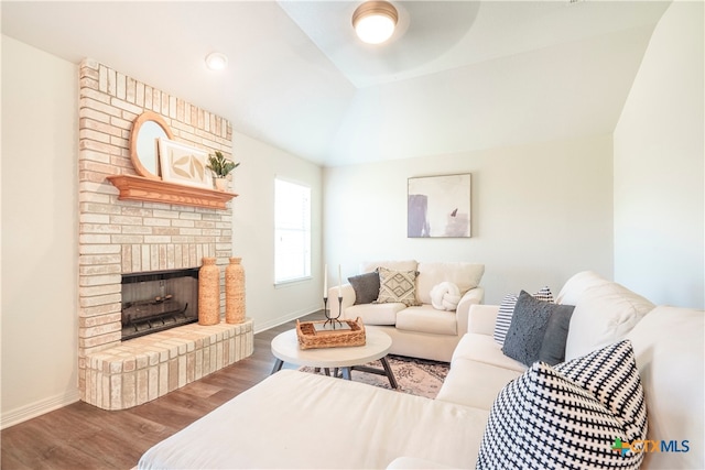 living room with a brick fireplace, wood-type flooring, and vaulted ceiling