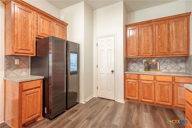 kitchen with dark wood-type flooring, backsplash, and stainless steel refrigerator