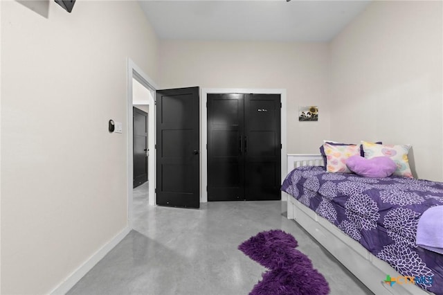 bedroom featuring concrete floors and baseboards