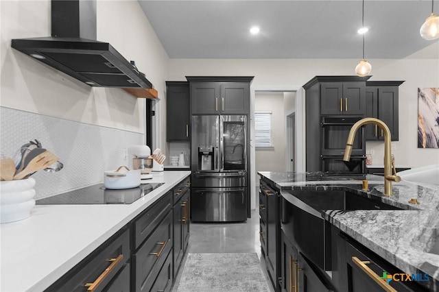 kitchen featuring hanging light fixtures, backsplash, finished concrete floors, wall chimney range hood, and black appliances