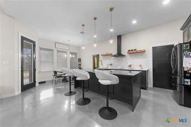 kitchen featuring wall chimney range hood, finished concrete floors, open shelves, and freestanding refrigerator