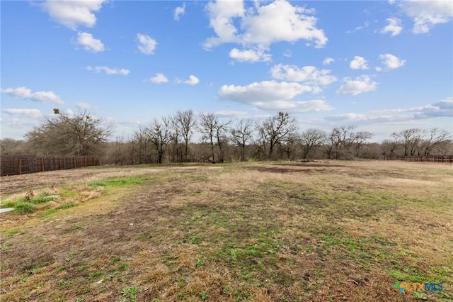 view of yard with fence and a rural view