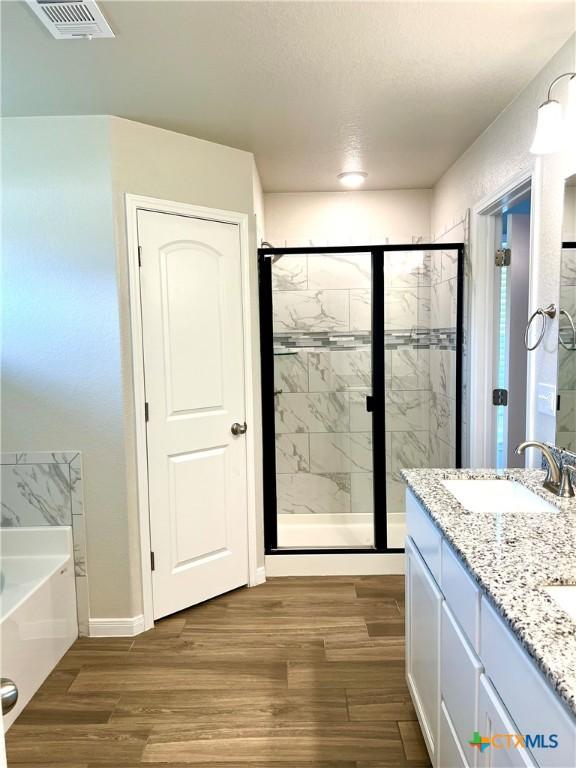 8302 Ridge Crest Dr, Killeen, TX 76542 - full bath featuring a garden tub, a stall shower, wood finished floors, and double vanity