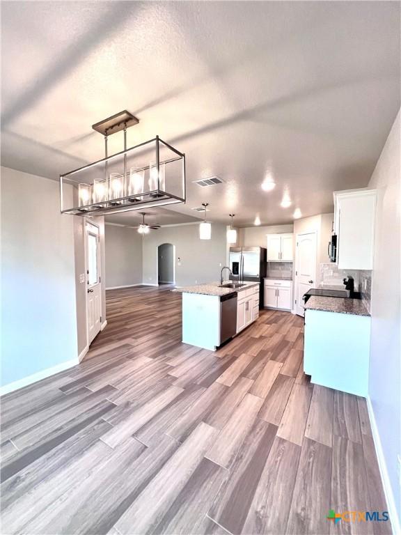 8302 Ridge Crest Dr, Killeen, TX 76542 - kitchen with open floor plan, stainless steel appliances, a ceiling fan, white cabinets, and wood finished floors