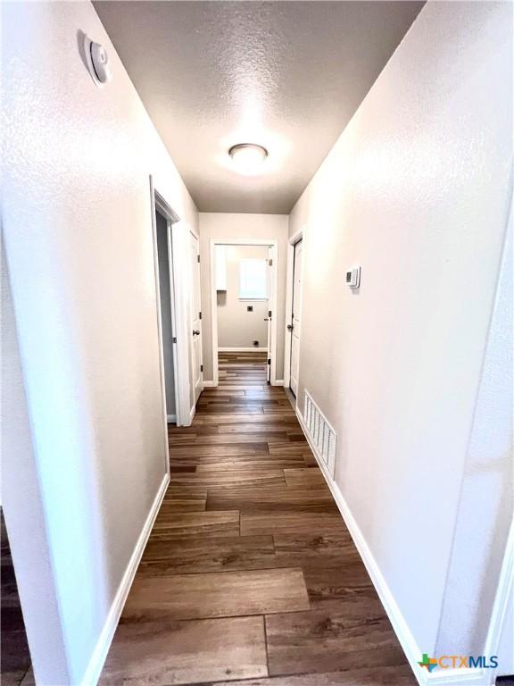 8302 Ridge Crest Dr, Killeen, TX 76542 - hallway featuring baseboards, a textured ceiling, and wood finished floors