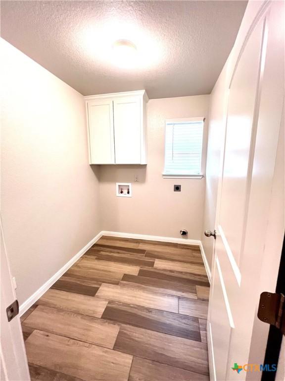8302 Ridge Crest Dr, Killeen, TX 76542 - laundry room with cabinet space, a textured ceiling, baseboards, electric dryer hookup, and wood finished floors