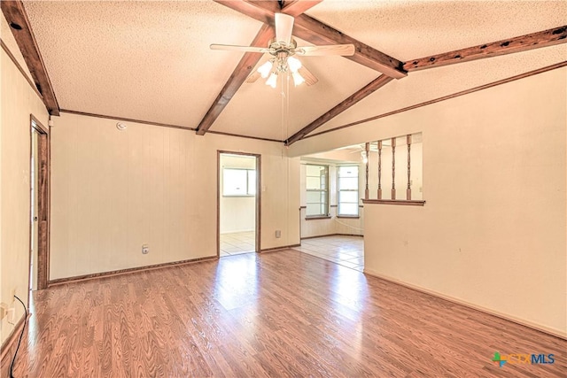 spare room featuring lofted ceiling with beams, wood finished floors, a textured ceiling, and ceiling fan