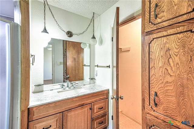 bathroom with tile patterned flooring, vanity, and a textured ceiling