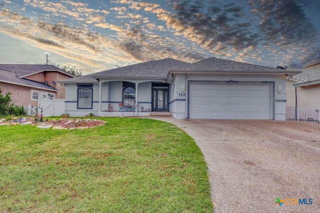 ranch-style home with a garage, a lawn, and covered porch