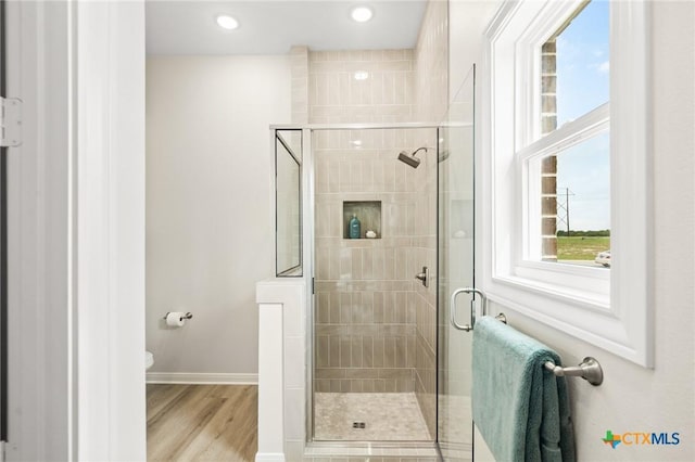 bathroom featuring toilet, wood finished floors, a stall shower, baseboards, and recessed lighting