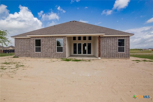 rear view of property with a patio area, a shingled roof, and brick siding