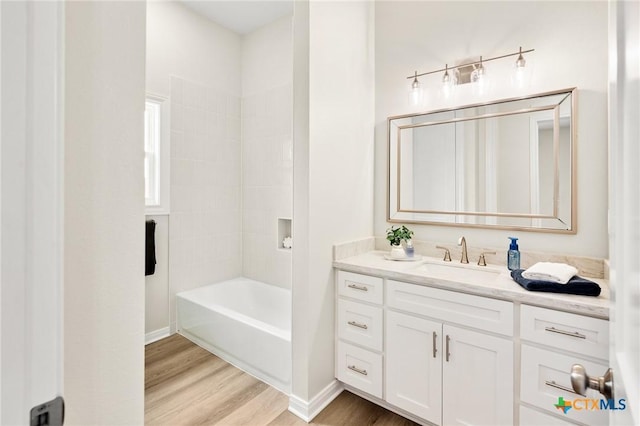 full bath featuring vanity, shower / bathtub combination, baseboards, and wood finished floors