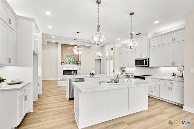kitchen with a ceiling fan, a kitchen island with sink, appliances with stainless steel finishes, and decorative backsplash