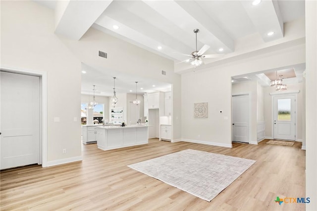 unfurnished living room featuring light wood-style floors, visible vents, ceiling fan with notable chandelier, and recessed lighting