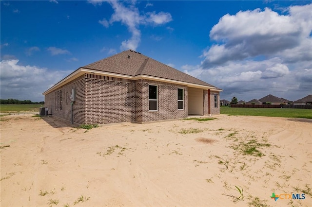 back of house featuring central AC unit and brick siding