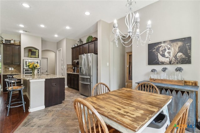 dining space with arched walkways, a chandelier, and recessed lighting