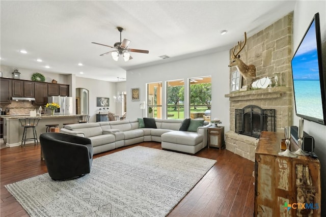 living area with ceiling fan, a stone fireplace, dark wood-style floors, and recessed lighting