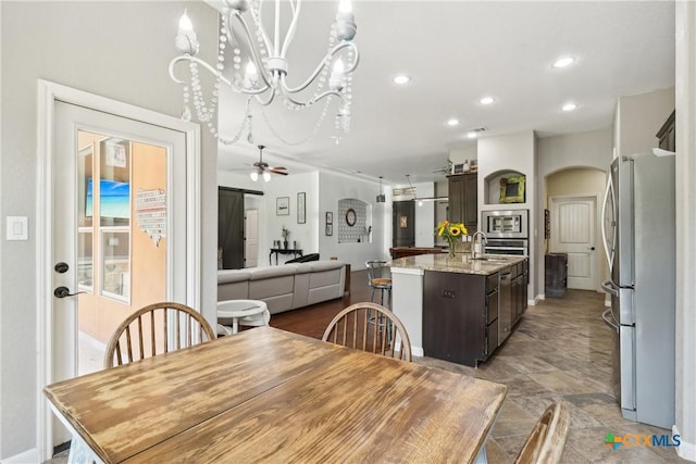 dining space with ceiling fan with notable chandelier, baseboards, arched walkways, and recessed lighting