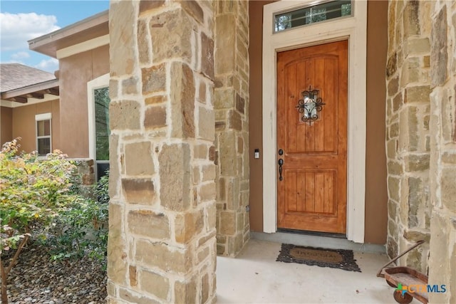 property entrance with stone siding and stucco siding