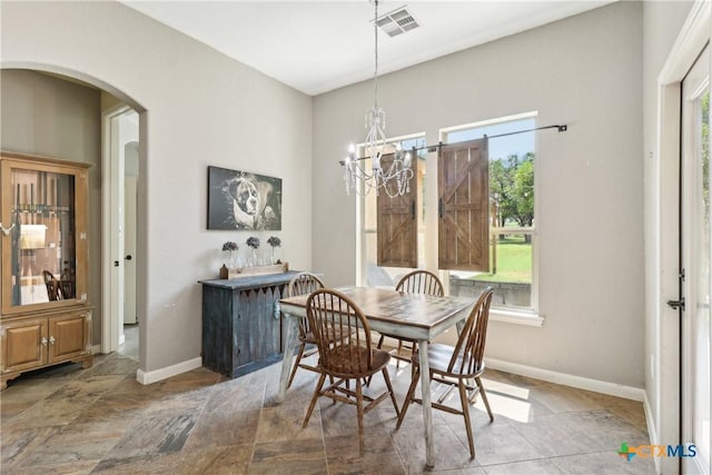 dining room with arched walkways, a chandelier, visible vents, and baseboards