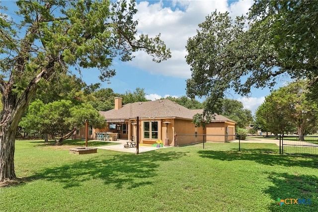 back of house featuring a yard, a patio area, a chimney, and fence