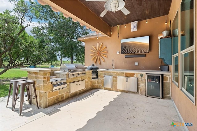 view of patio featuring grilling area, a ceiling fan, exterior kitchen, and a sink