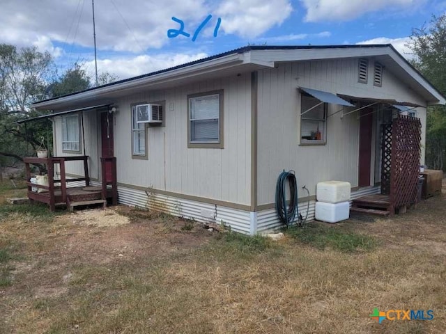 manufactured / mobile home with a front lawn and a wall mounted air conditioner