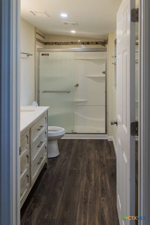 bathroom featuring vanity, hardwood / wood-style flooring, toilet, and a shower with door