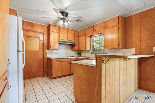 kitchen featuring cooktop, white fridge, a breakfast bar, and kitchen peninsula