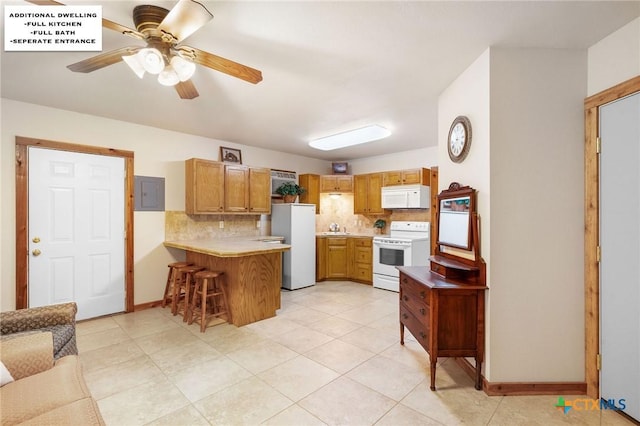 kitchen with white appliances, a kitchen breakfast bar, kitchen peninsula, ceiling fan, and backsplash